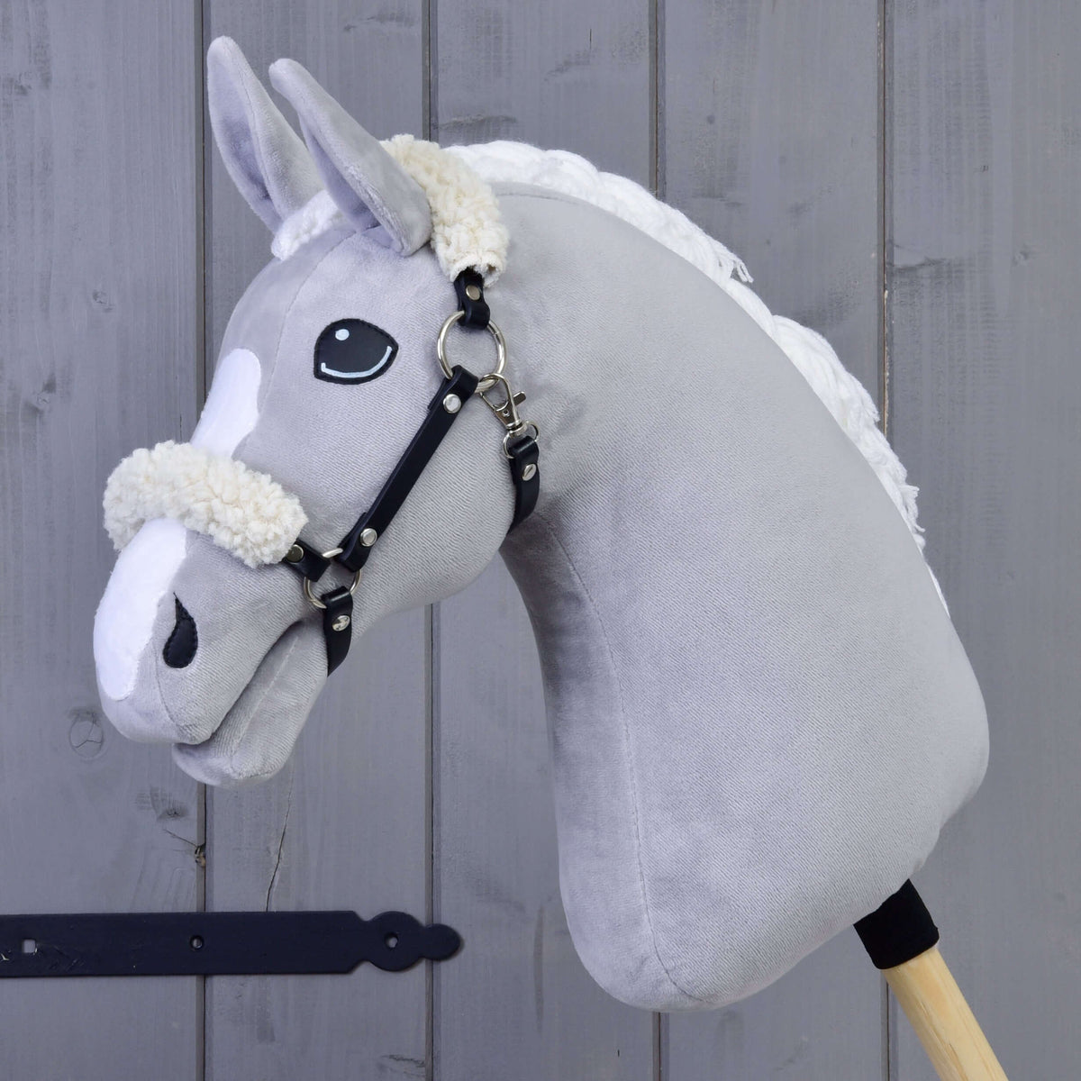 Grijze Hobby Horse met het zwarte kunstleren halster met crème bont op de neusriem en achter de oren