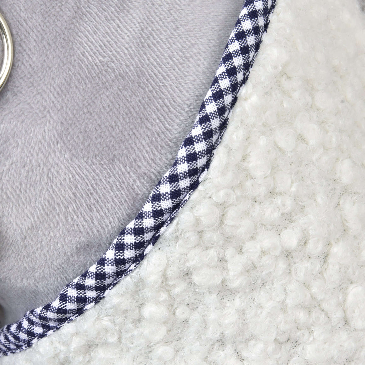 Close-up van de hals van de deken cube blauw met marineblauw-wit geruite bies op crème krullend fleece