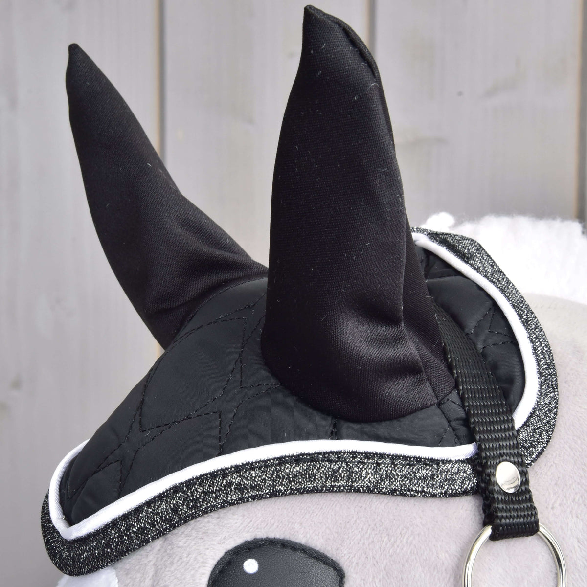 Close-up van het oornetje uit de Set Thermo Black Queen met zwarte oren en glinsterende rand op een grijze Hobby Horse