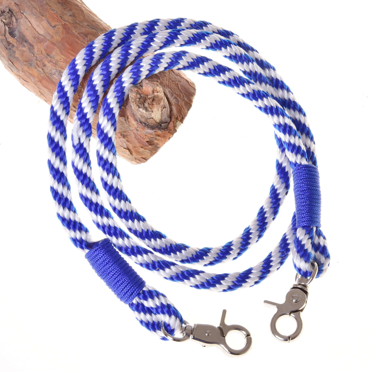 Blue and white twisted rope reins for Hobby Horse with blue wraps and two silver snap hooks over a branch