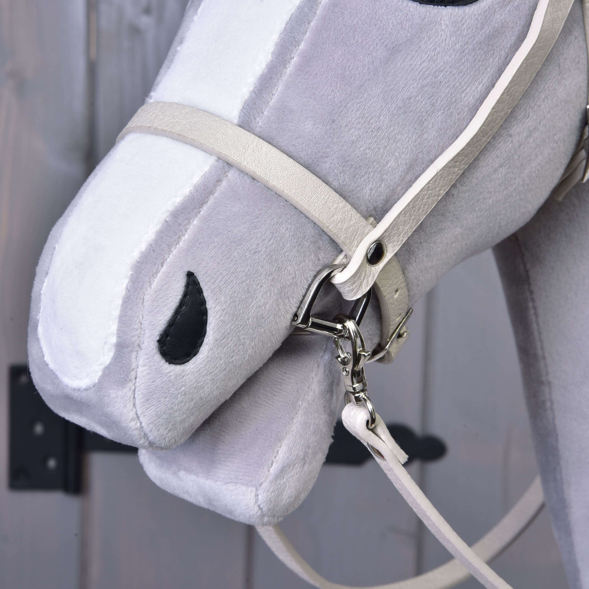 Close-up of the cream noseband and snap hook with rein on the muzzle of a grey Hobby Horse