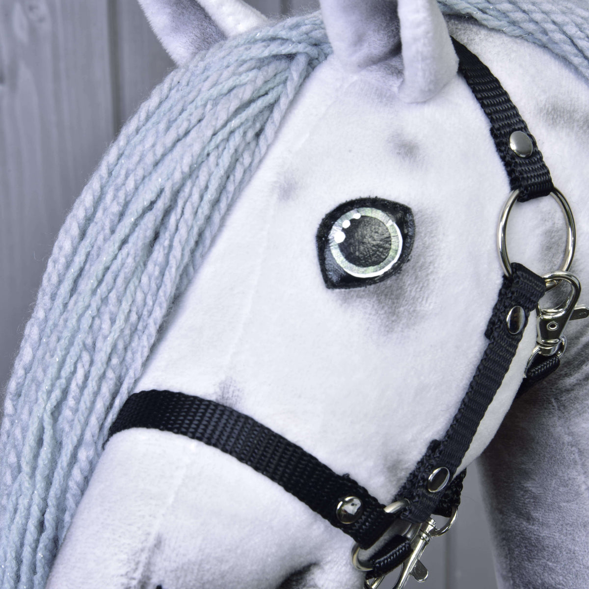 Gros plan sur l’œil et le licol noir du Hobby Horse Licorne Silver, crinière gris clair en fil aux fines paillettes argentées