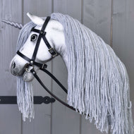 Side view of the Hobby Horse Unicorn Silver in its black bridle with reins, the long grey yarn mane falling over the neck