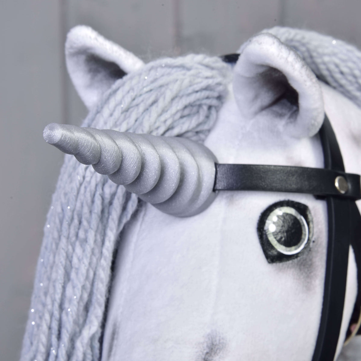 Gros plan sur la corne spirale argentée du Hobby Horse Licorne Silver, fixée à la bride noire entre les oreilles