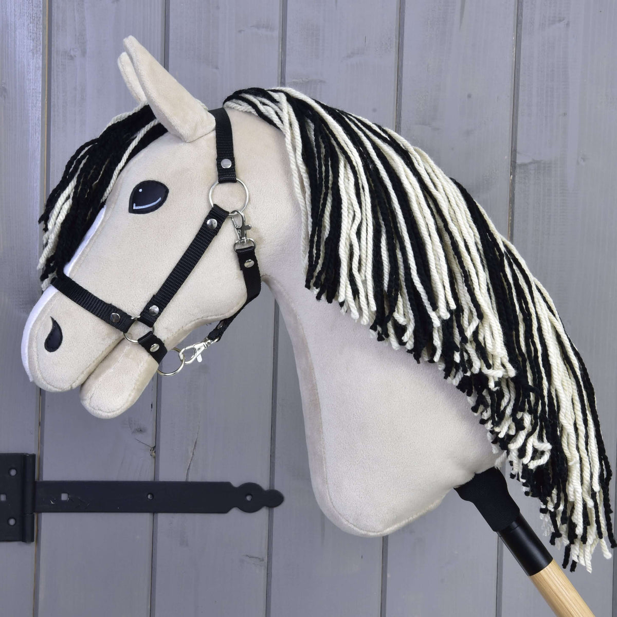 Hobby Horse Aurora de profil, tête crème, licol noir et longue crinière en fil noir et blanc le long de l’encolure