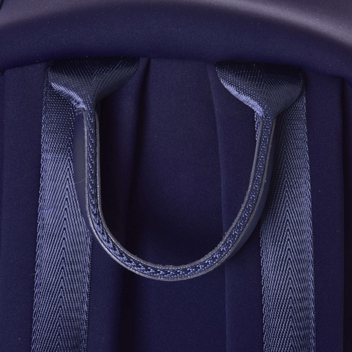 Gros plan de la poignée en sangle bleu marine entre les bretelles du sac à dos Hobby Horse