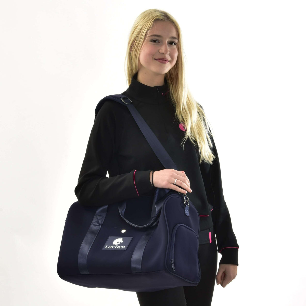 Jeune fille blonde en sweat-shirt noir portant à l’épaule un sac de sport Hobby Horse bleu marine au logo blanc LarDen