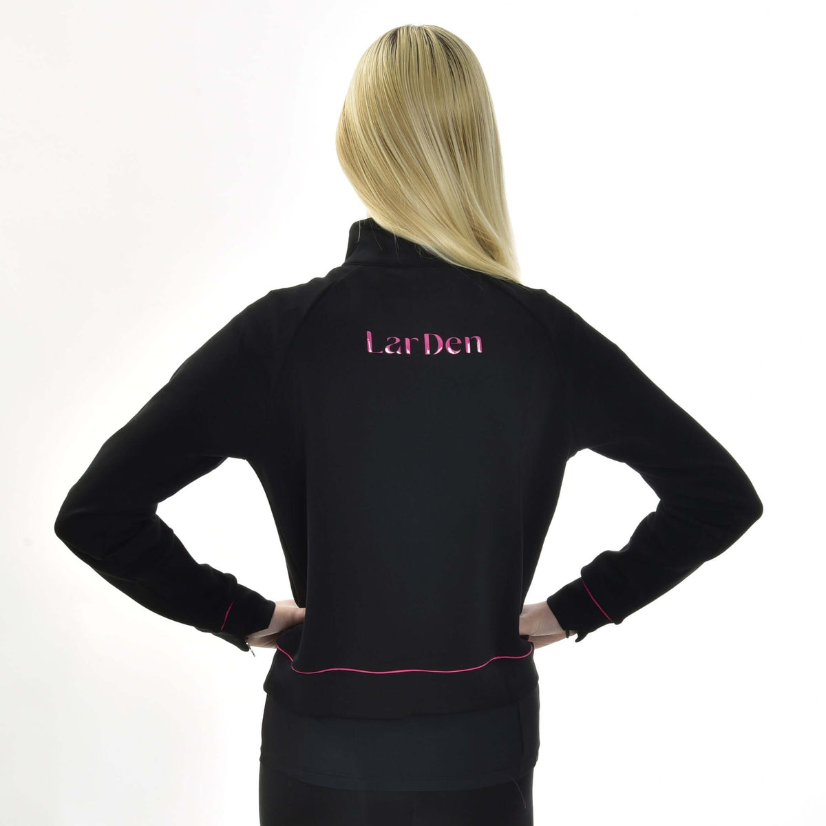 Blond meisje van achteren, handen in de zij, in de zwarte Hobby Horse LarDen sweatshirt met roze letters op de rug