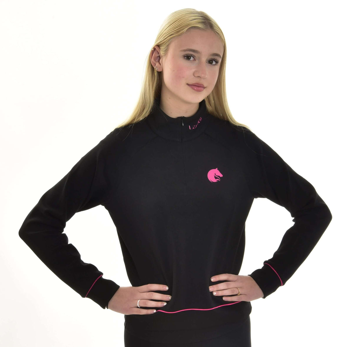 Blond meisje met handen in de zij in de zwarte Hobby Horse sweatshirt met roze paardenhoofdlogo op de borst en roze biesjes