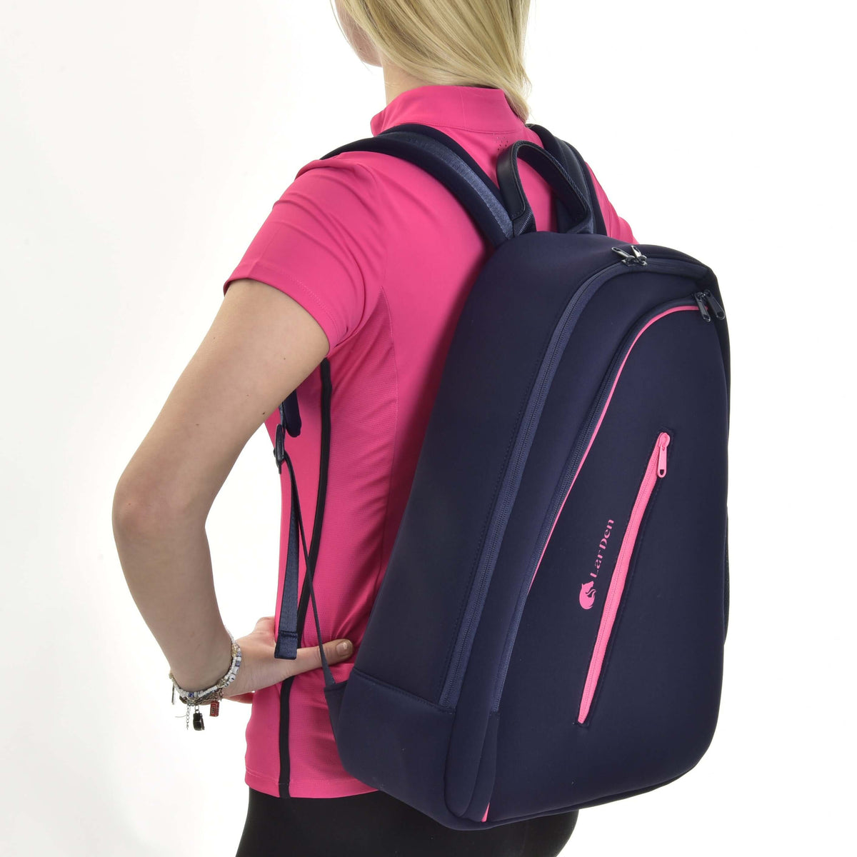 Jeune fille blonde en haut de sport rose portant le sac à dos Hobby Horse bleu marine, vue de côté