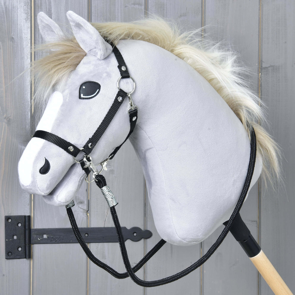 Grijze Hobby Horse met blonde manen en zwart halster, de zwarte gevlochten teugels aan beide kanten vastgeklikt en los hangend