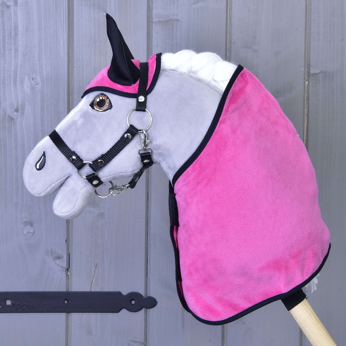 Hobby Horse gris aux yeux marron avec licol noir portant la couverture et le bonnet d'oreilles veloutés rose vif