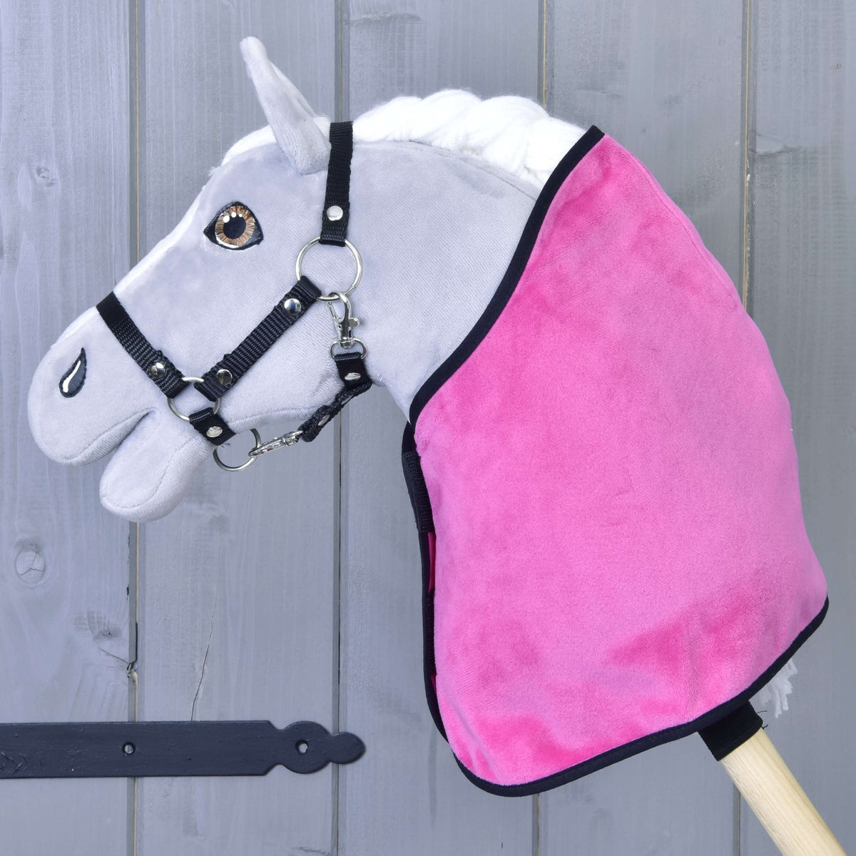 Hobby Horse gris avec licol noir portant seulement la couverture veloutée rose vif à bordure noire