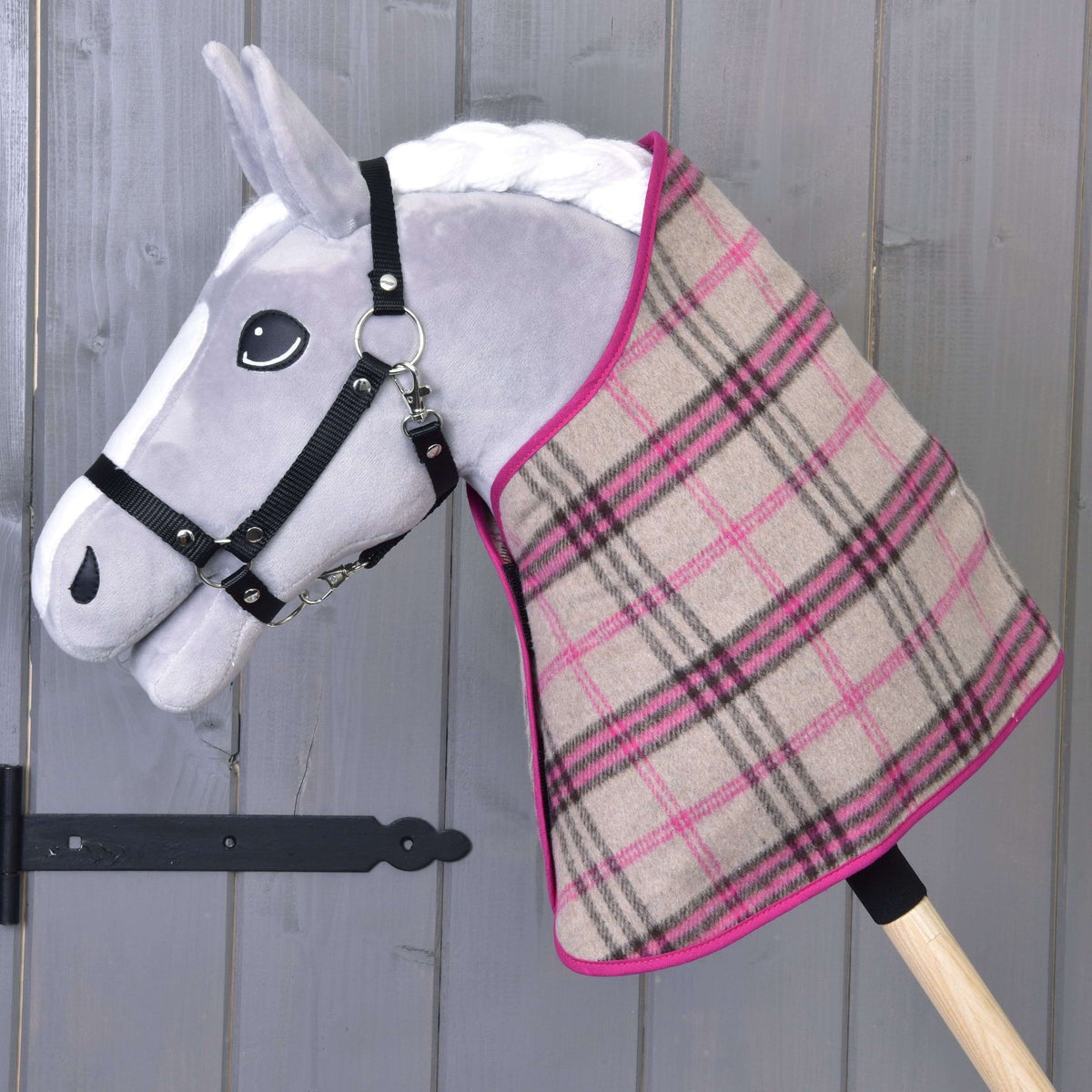 Grijze Hobby Horse met zwart halster die alleen de beige-roze geruite deken met roze bies draagt