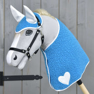 Hobby Horse en peluche grise avec licol noir portant la couverture bleue bouclée et le bonnet d’oreilles, cœur blanc et oreilles blanches