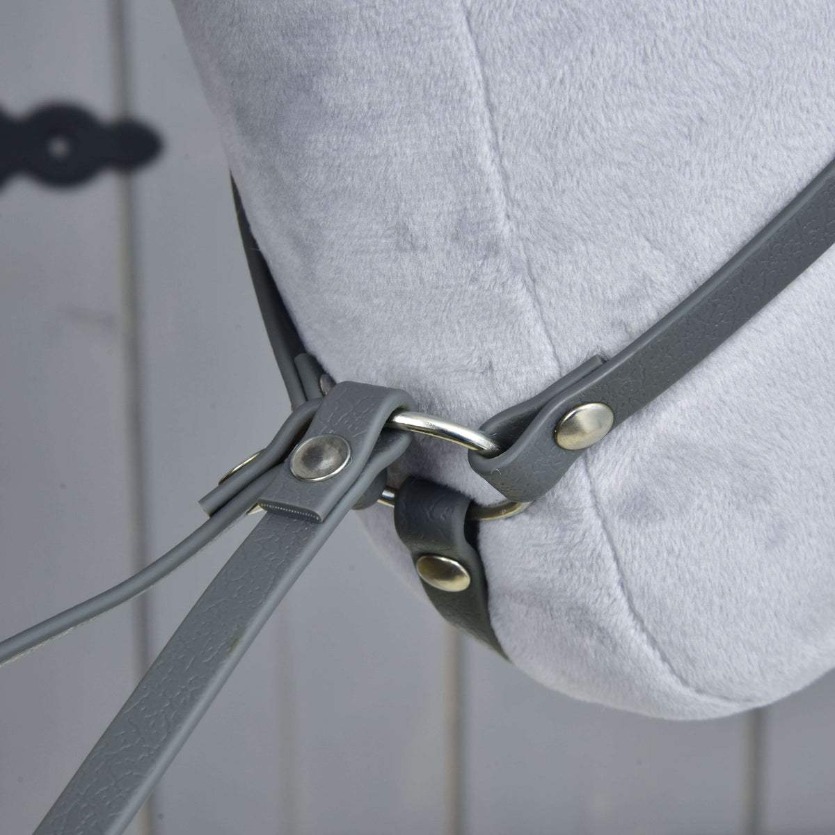Close-up onder de pluche hals, waar de halsriem van de martingaal bij een zilveren ring met klinknagels in de takken overgaat