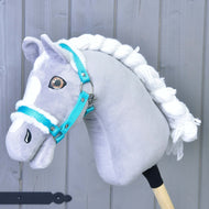 Een grijze pluche Hobby Horse met witte gevlochten manen en bruine ogen draagt de turquoise halster met wit bont