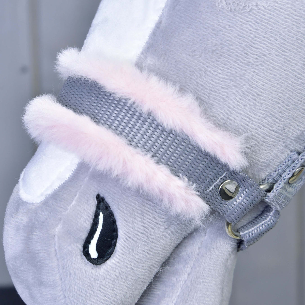 Close-up of the grey webbing noseband with soft light pink fur padding and a silver rivet on a grey plush Hobby Horse