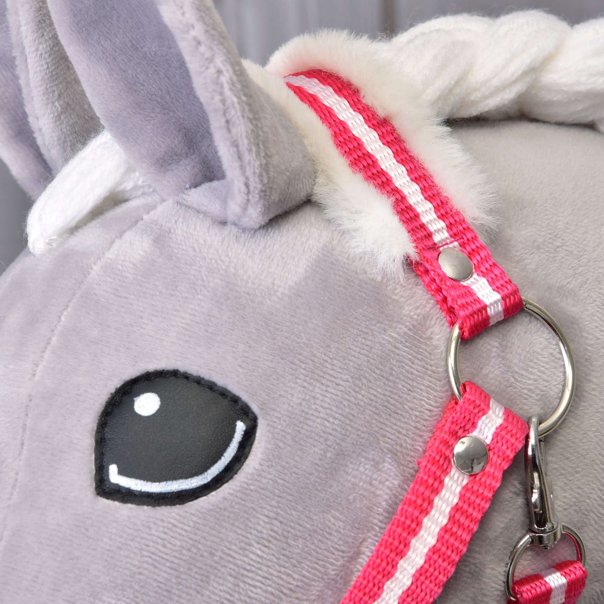 Close-up van het rood gestreepte kopstuk met wit bont bij het oor van een grijze Hobby Horse, met ring en musketon