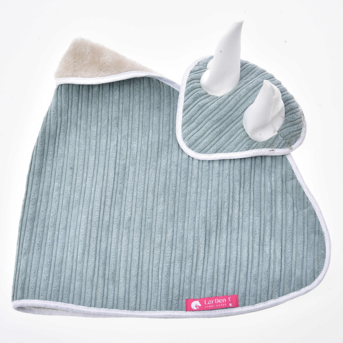 Couverture et bonnet d’oreilles en velours côtelé vert sauge à plat, polaire crème à l’encolure et étiquette rose LarDen en bas
