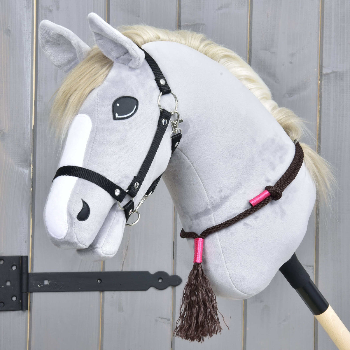 Bruine cordeo van de Touwset Noir Cocoa met roze omwikkelingen en bruin kwastje op een grijze Hobby Horse met zwarte halster