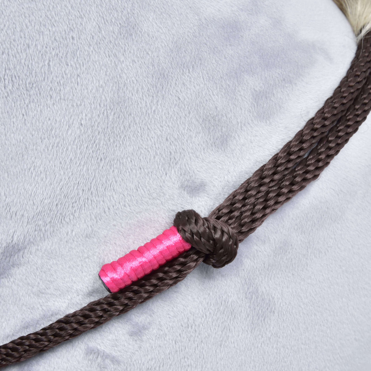 Knoop in bruin touw met felroze omwikkeld uiteinde van de Touwset Noir Cocoa op een grijze pluche hals