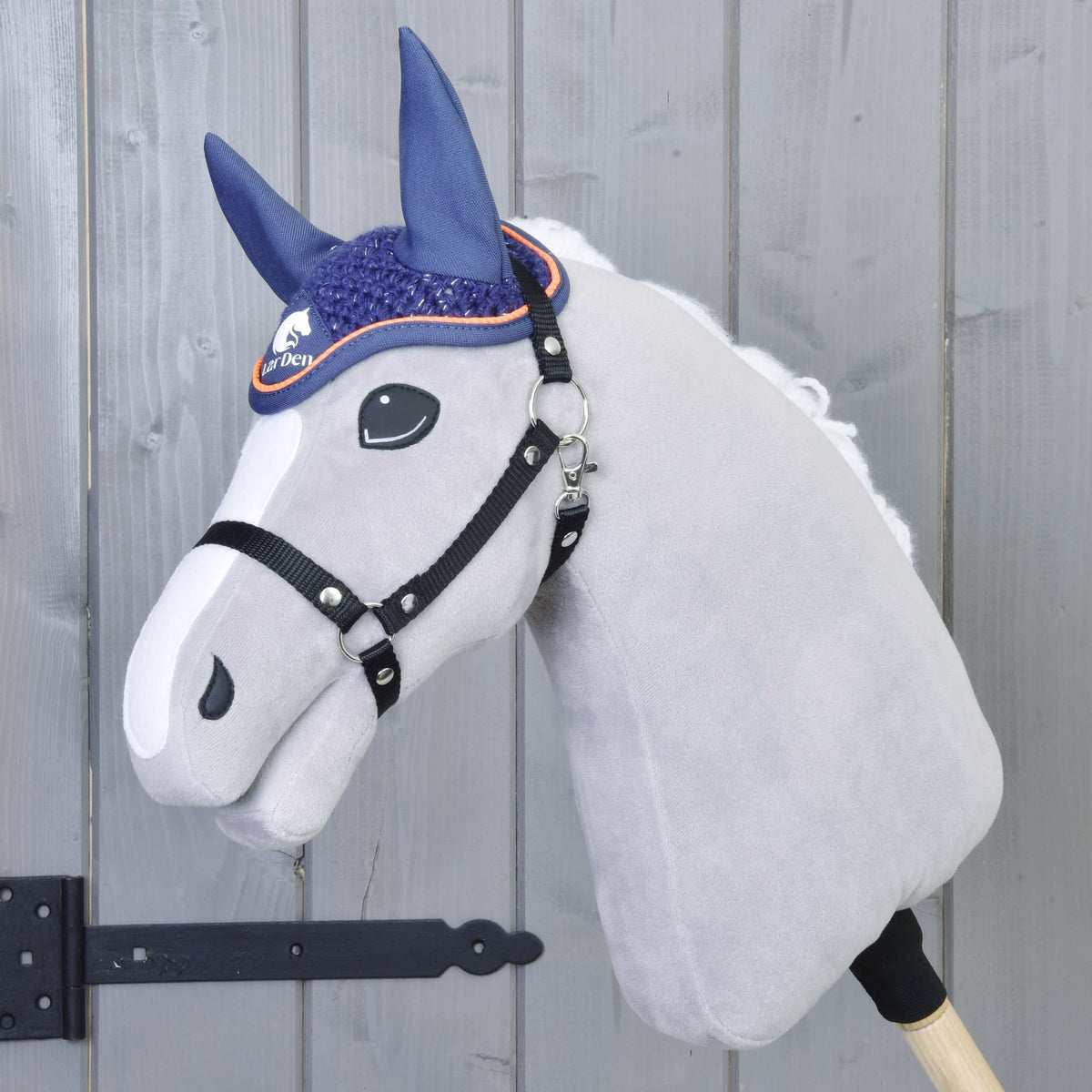 Hobby Horse gris en peluche à liste blanche et licol noir portant le bonnet d’oreilles bleu marine au crochet à passepoil orange