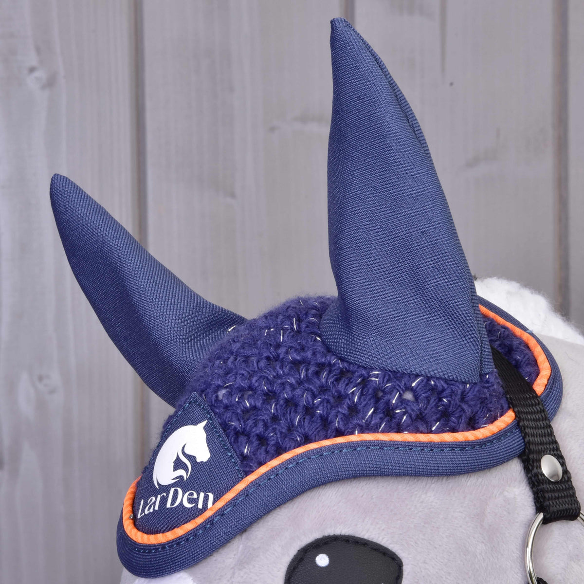 Bonnet d’oreilles bleu marine vu de côté, hautes oreilles en tissu, crochet pailleté, passepoil orange et logo LarDen