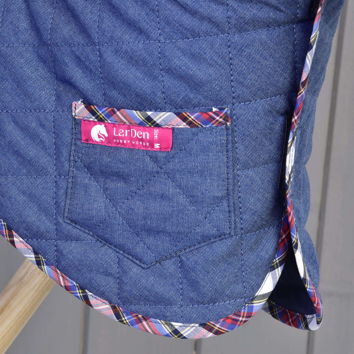 Detail of the pocket on the Hobby Horse Set Jeans blanket with pink LarDen label, diamond quilting and red-blue tartan trim