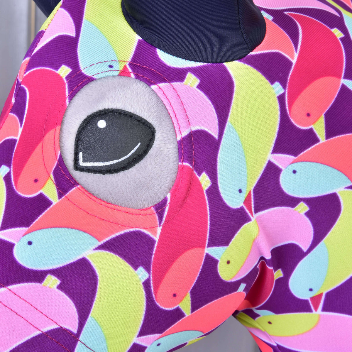 Close-up of the eye opening in the Bird protective suit on a Hobby Horse: pink, lime and light blue birds on purple