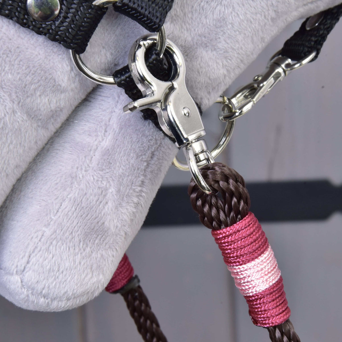 Close-up of the snap hook and pink and burgundy wrap of the dark brown York reins at the halter of a Hobby Horse