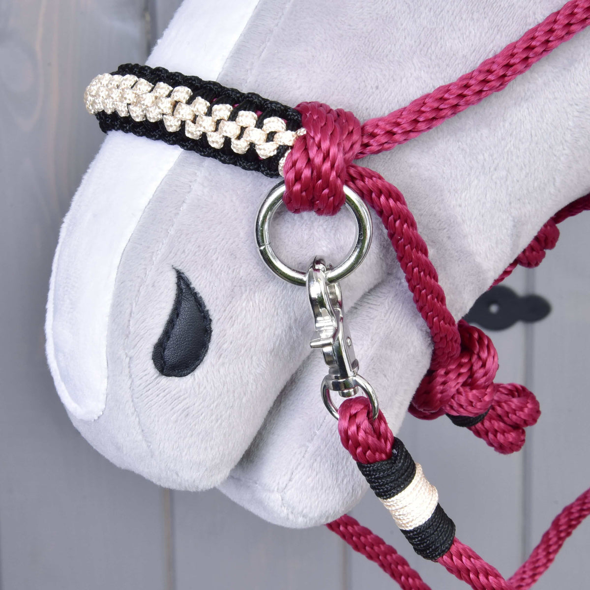 Close-up van de zwart-crème gevlochten neusriem en de musketonhaak van Touwset Burgundy op een Hobby Horse