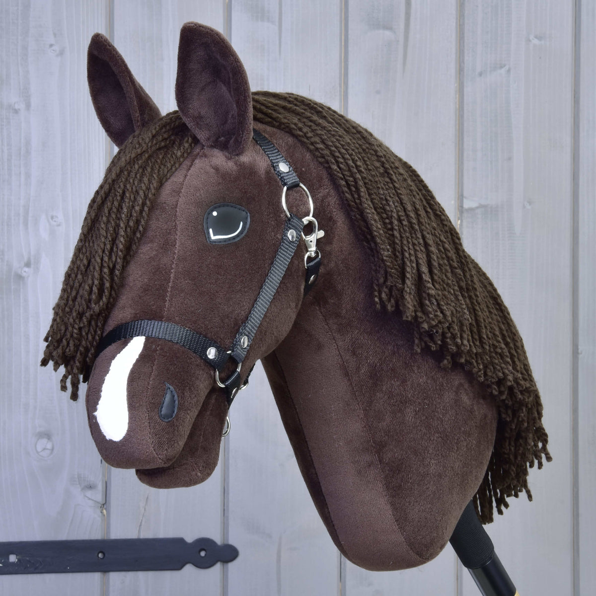 Hobby Horse Chianti met zwart halster van LarDen, een donkerbruin pluchen paard met witte bles en bruine manen van garen