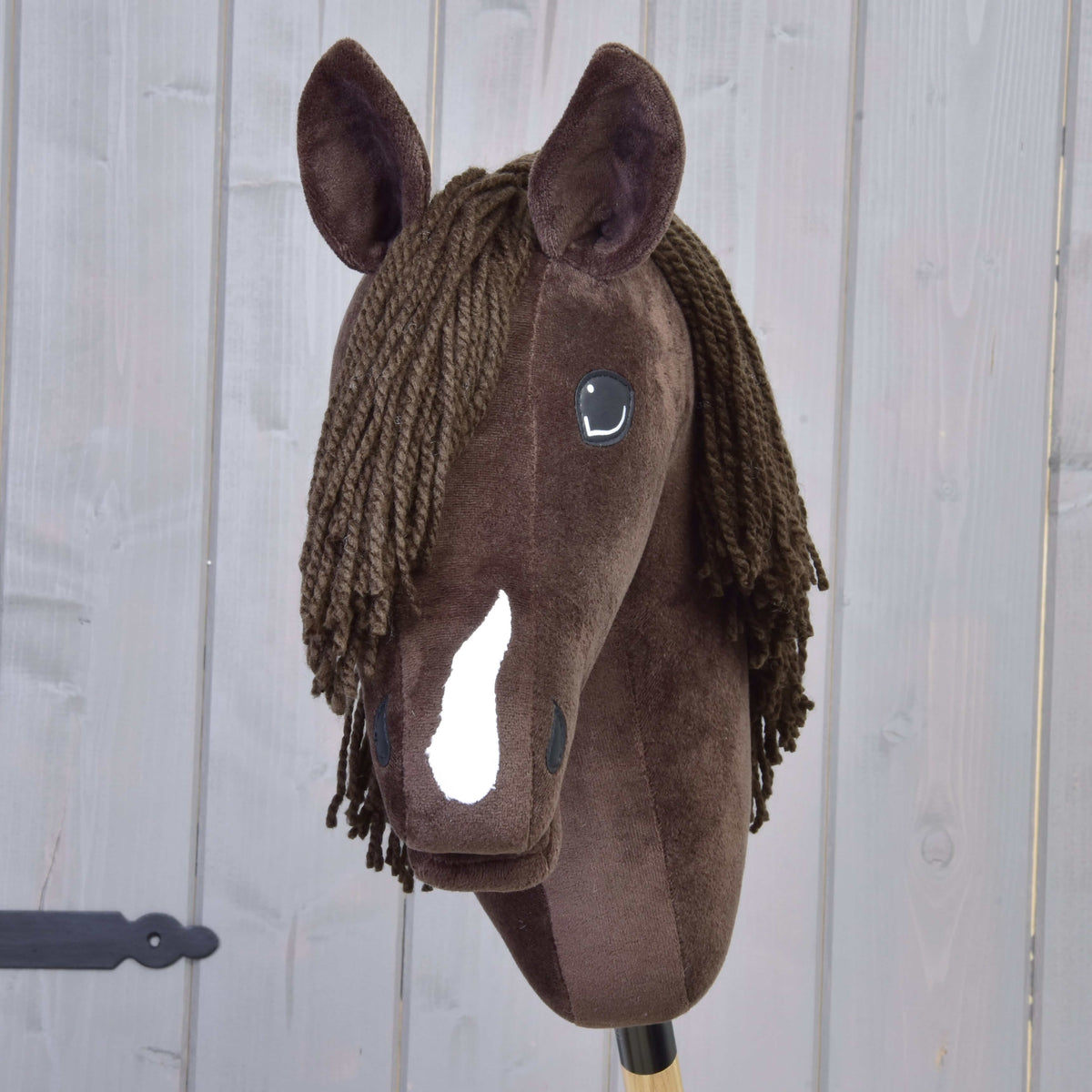 Donkerbruine Hobby Horse van voren zonder halster, met witte bles en bruine kuif van garen