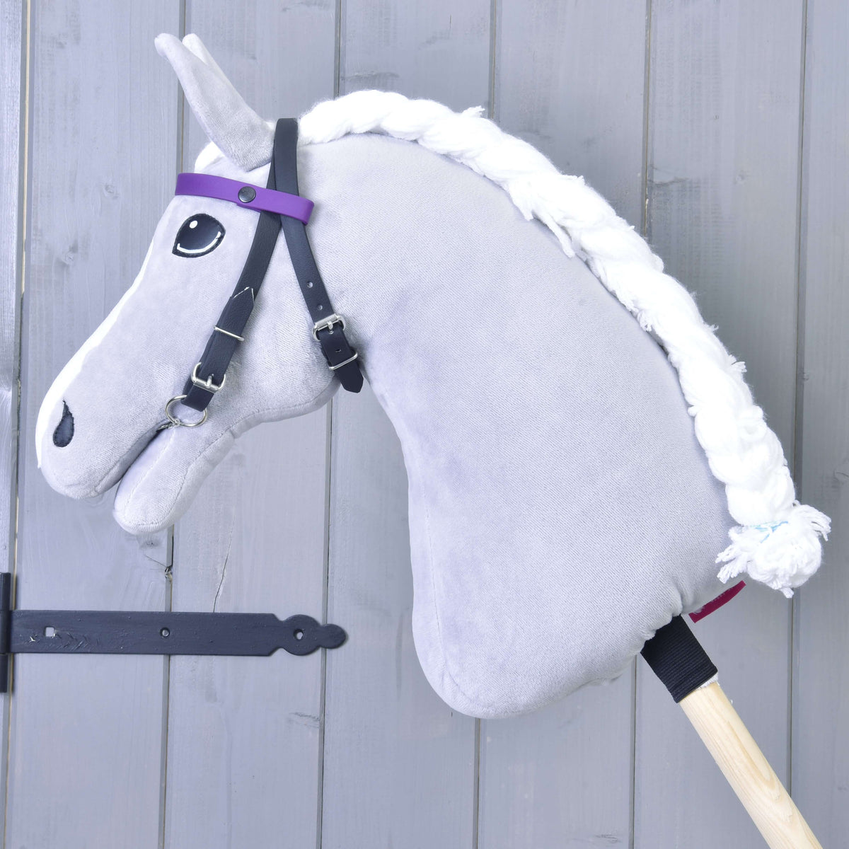 Grey Hobby Horse with a braided white mane wearing the black bridle with the plain purple browband