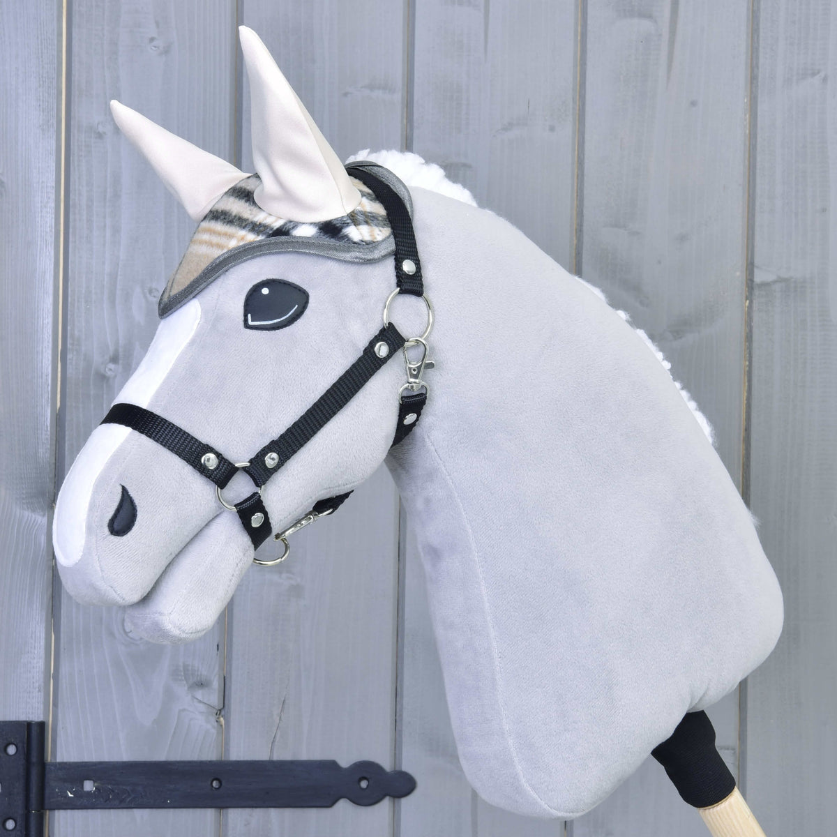 Hobby Horse gris clair au licol noir portant le bonnet d’oreilles beige à carreaux aux oreilles crème