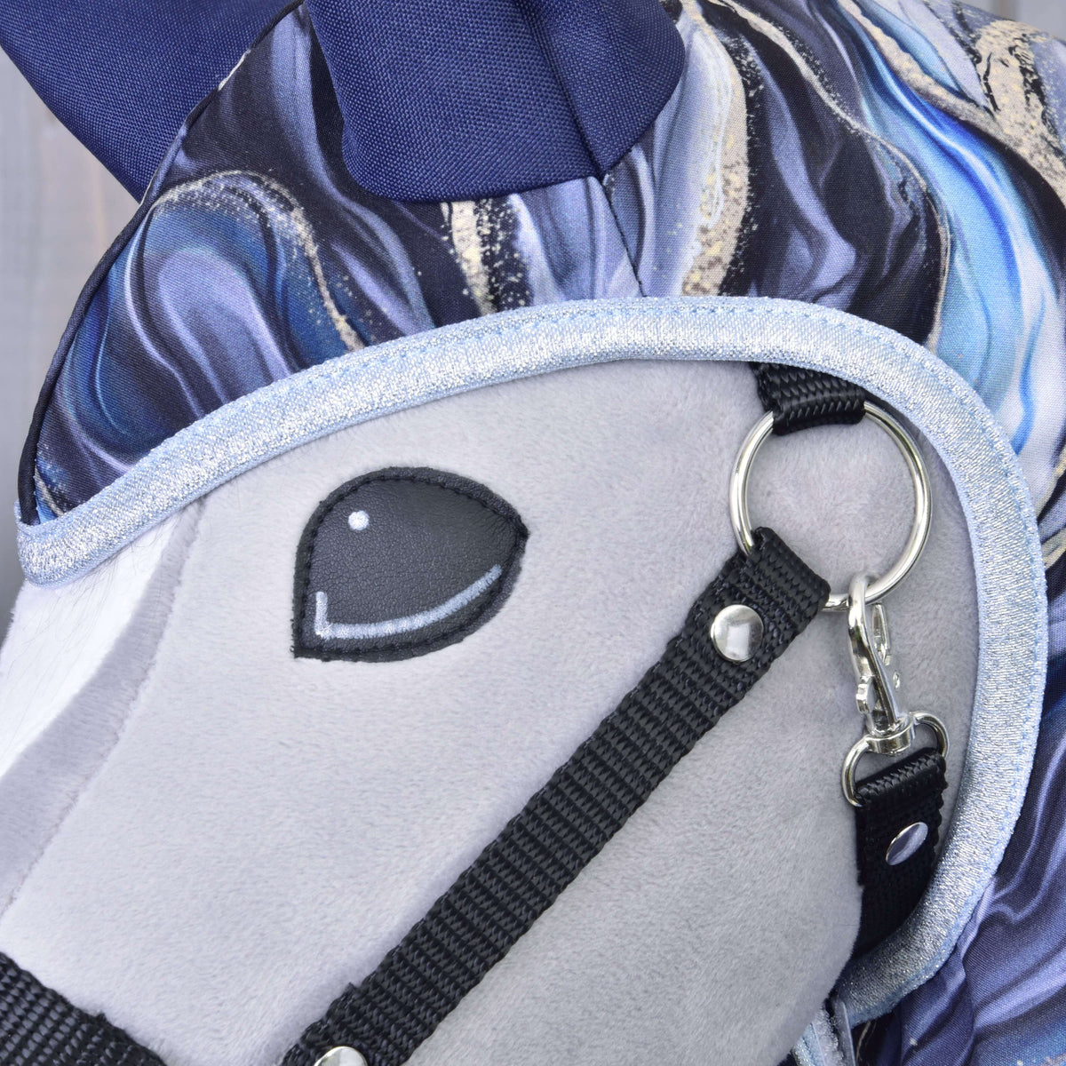 Gros plan sur la bordure pailletée bleu pâle autour de la tête d’un Hobby Horse gris dans l’imperméable Galaxy Cobalt, oreille marine