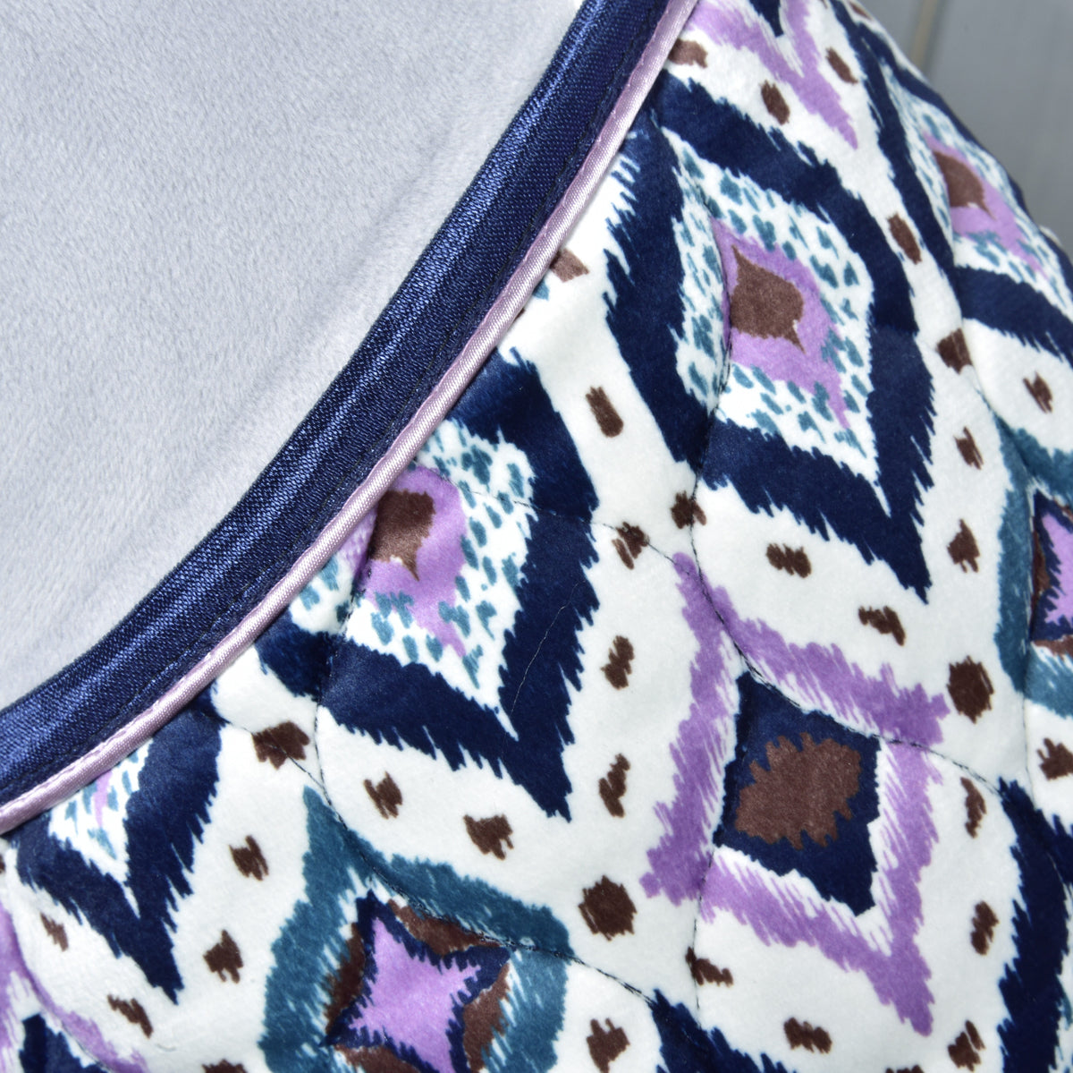 Close-up of the Indian blanket print in navy, lilac, teal and brown, with navy binding and lilac piping on a grey neck