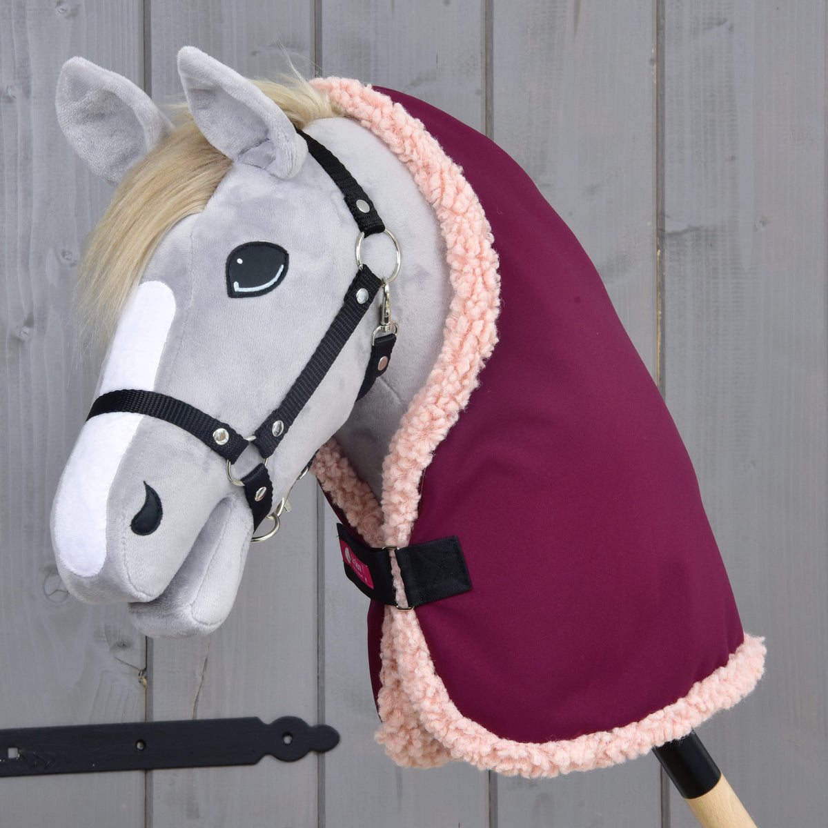 Hobby Horse gris à crinière blonde et licol noir portant la couverture d'écurie Royal Burgundy bordée de polaire rose pâle