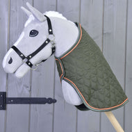 Lichtgrijze Hobby Horse met zwart halster draagt de gewatteerde olijfgroene deken met oranje bies
