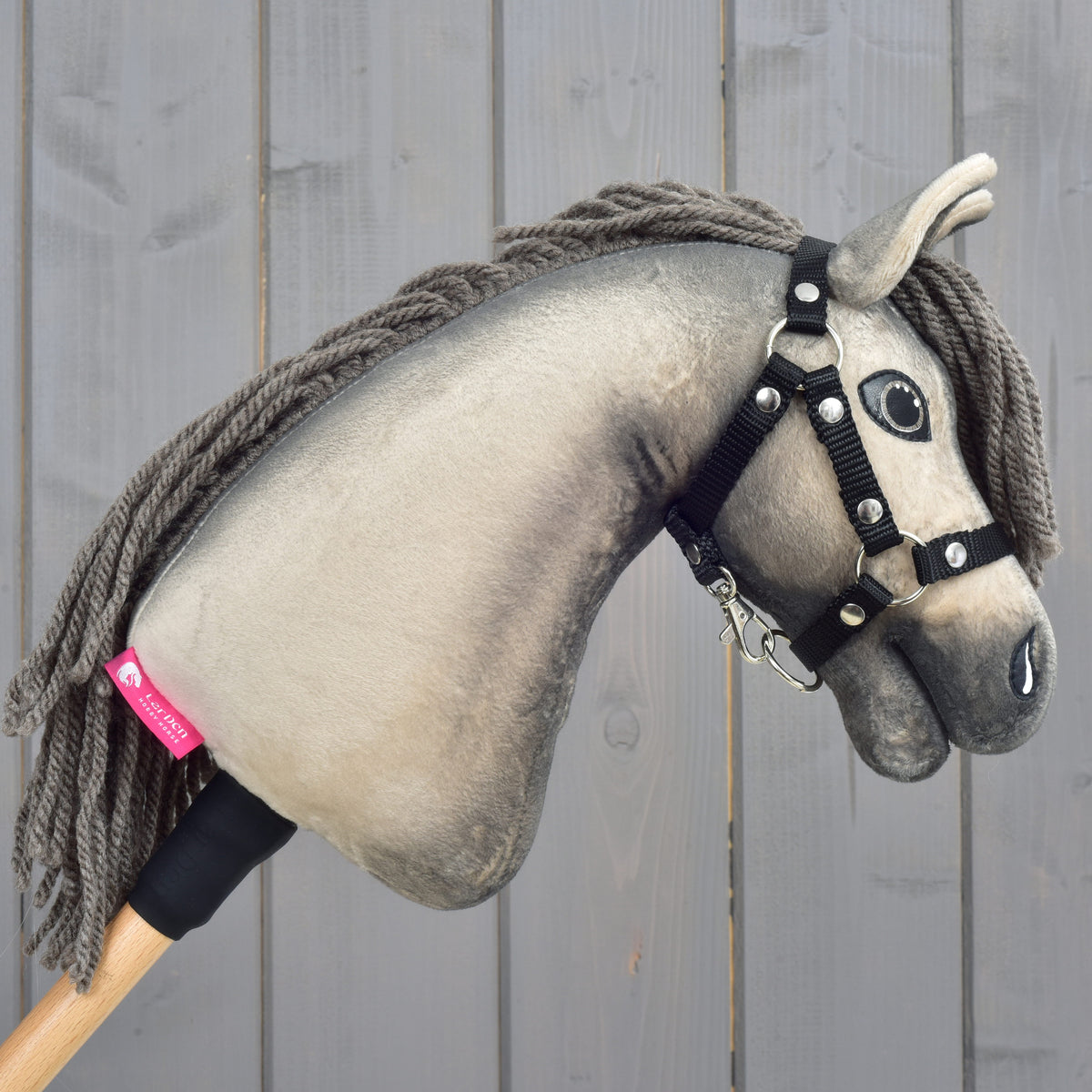 Hobby Horse Dusty facing right with the pink LarDen label on the neck, grey-brown yarn mane and black halter