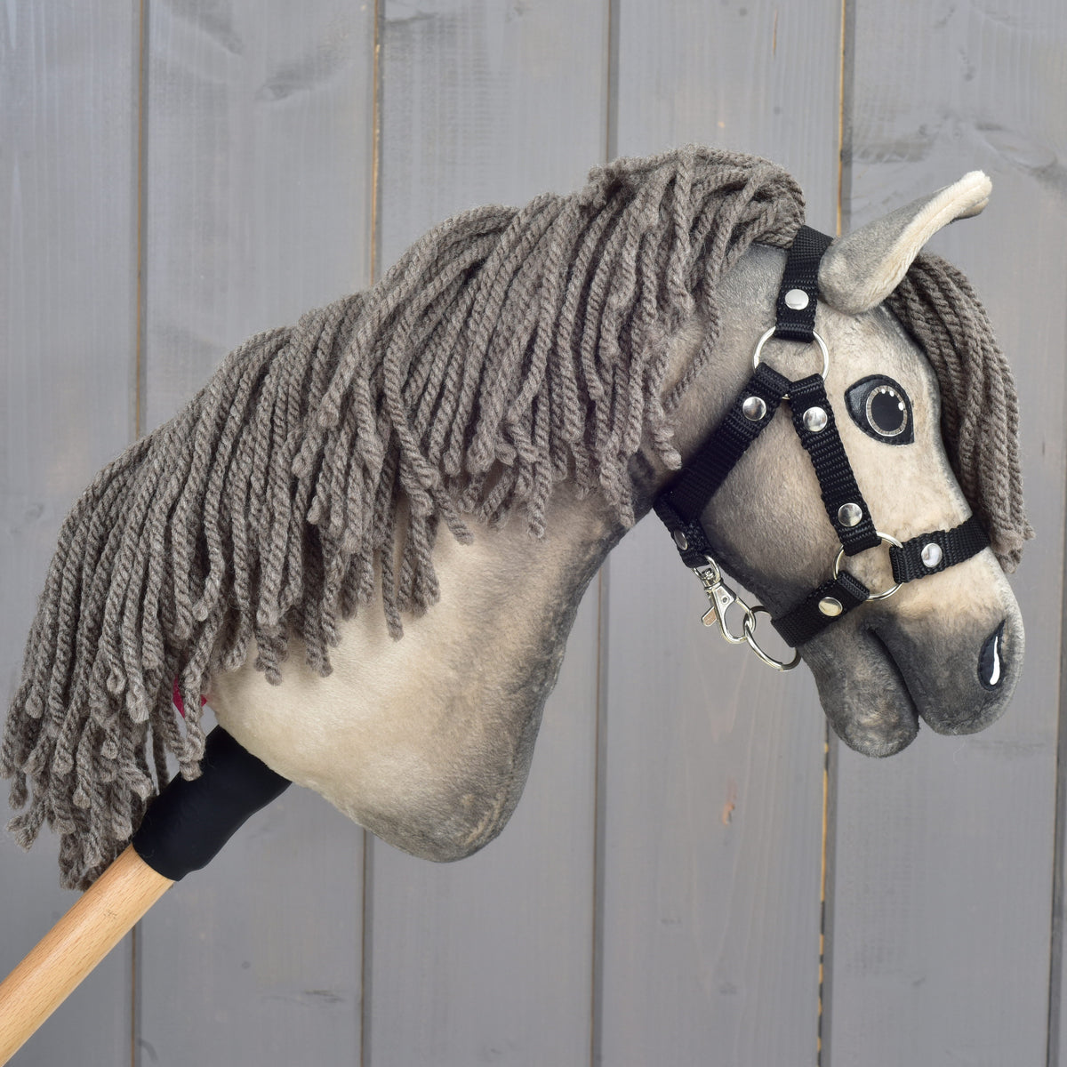Hobby Horse Dusty facing right with its long grey-brown yarn mane hanging over the near side of the neck