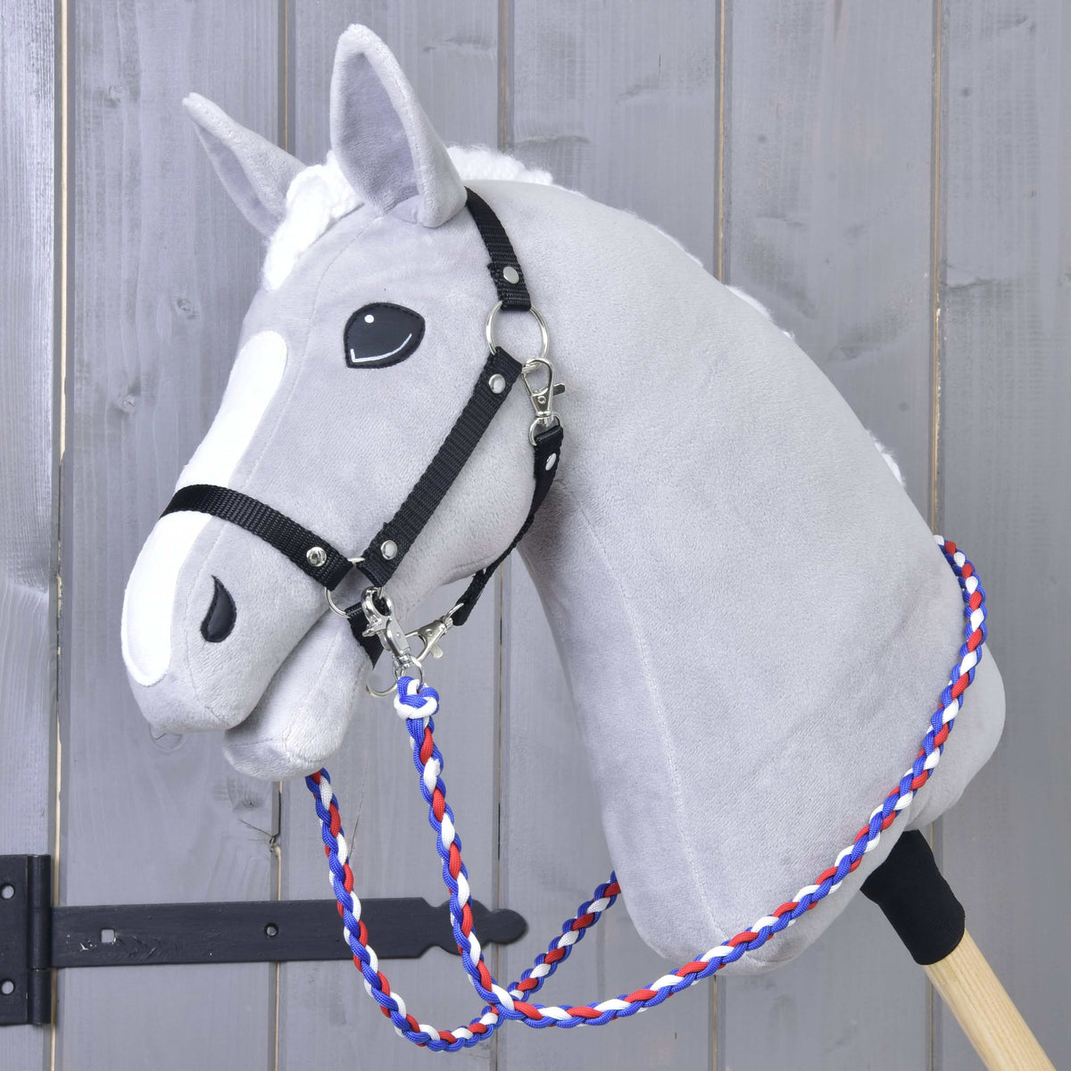 Lichtgrijze Hobby Horse met zwart halster en gevlochten blauw-rood-witte Teugels Flag CZ om de hals