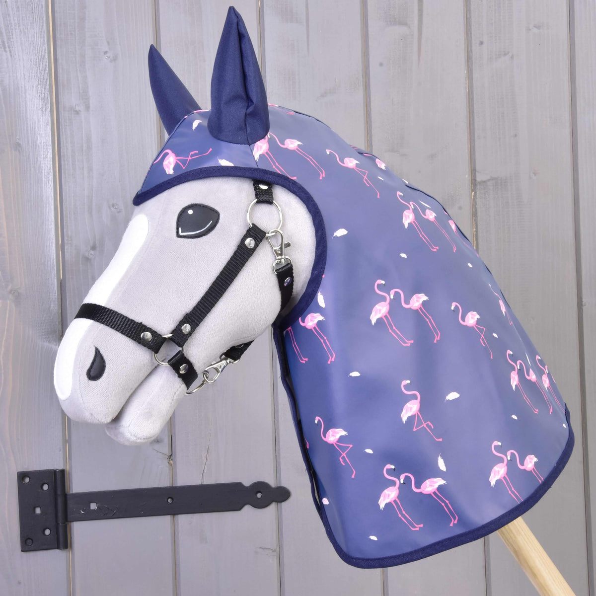 Grijze Hobby Horse met zwart halster in de blauwpaarse regenjas met roze flamingoprint en marineblauwe oortjes