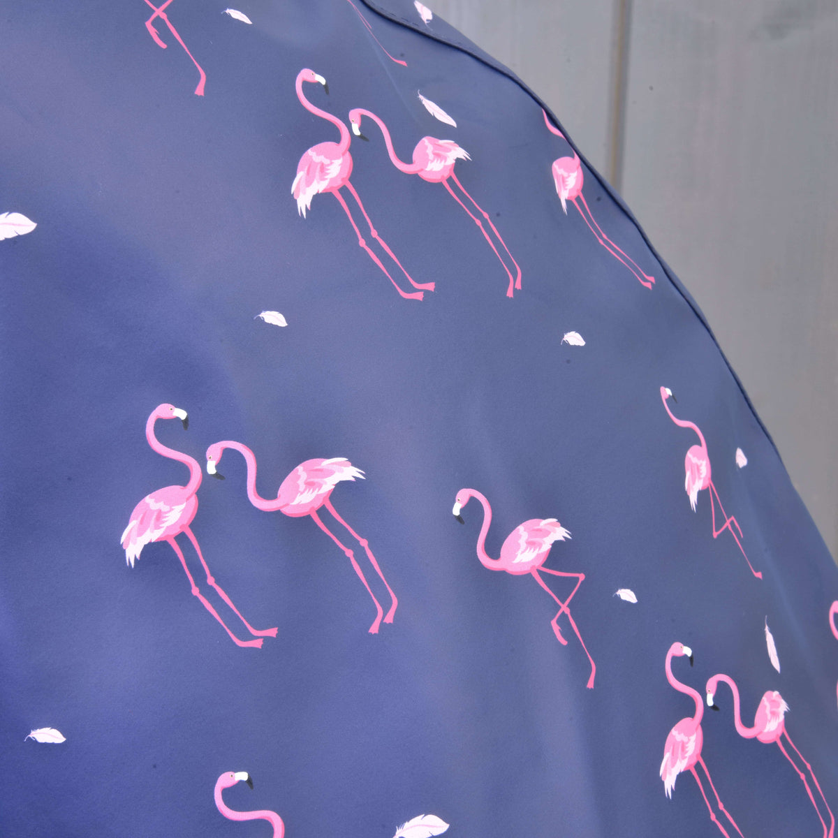 Close-up van de print met roze flamingo’s en witte veertjes op de blauwpaarse stof van de regenjas voor Hobby Horse