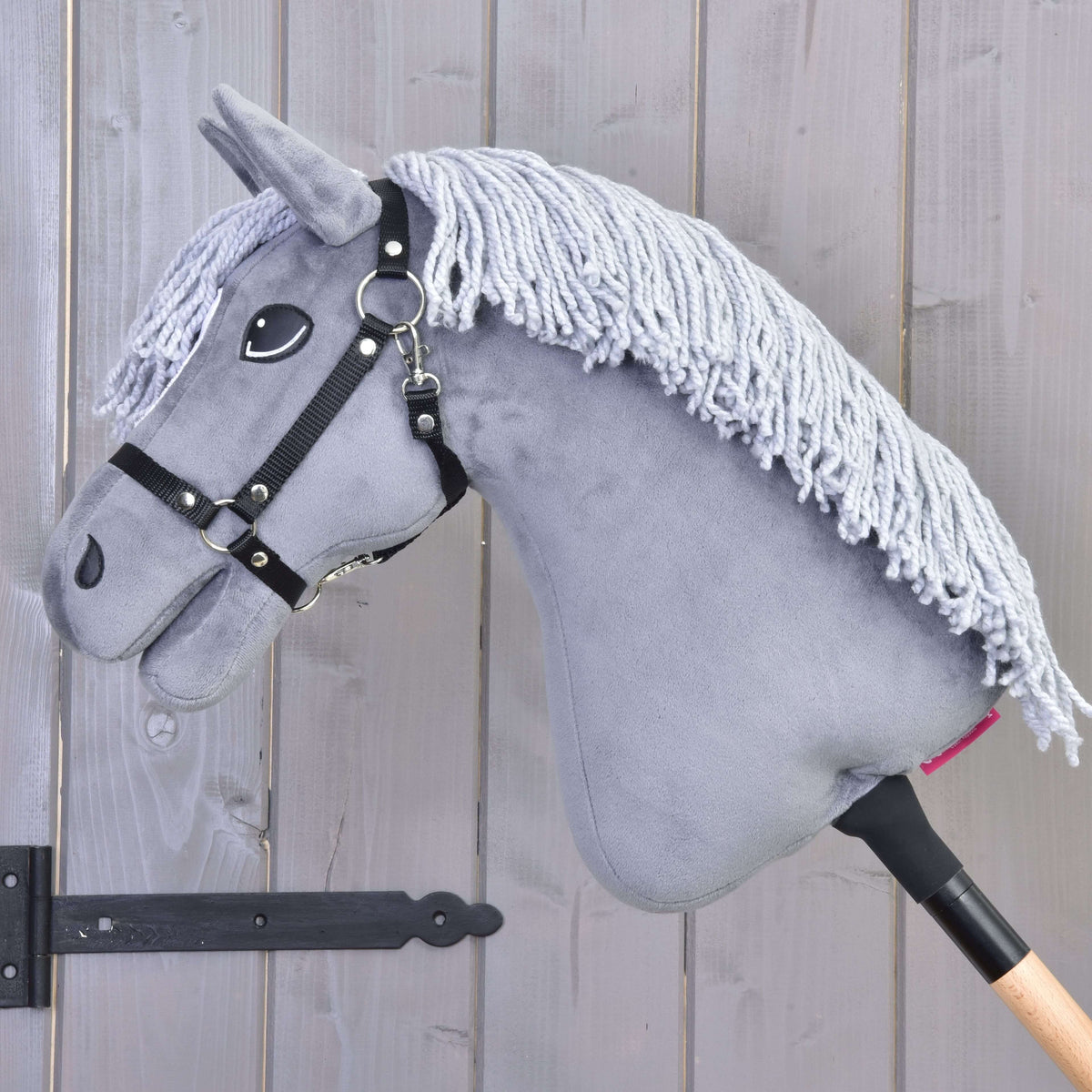 Hobby Horse Grace van links in profiel met lange lichtgrijze manen van garen over de grijze hals en zwarte halster