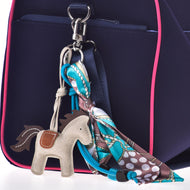 Sleutelhanger Paard Grijs aan de ring van de riem van een marineblauwe tas met roze bies, met turquoise kralen en geknoopte sjaal