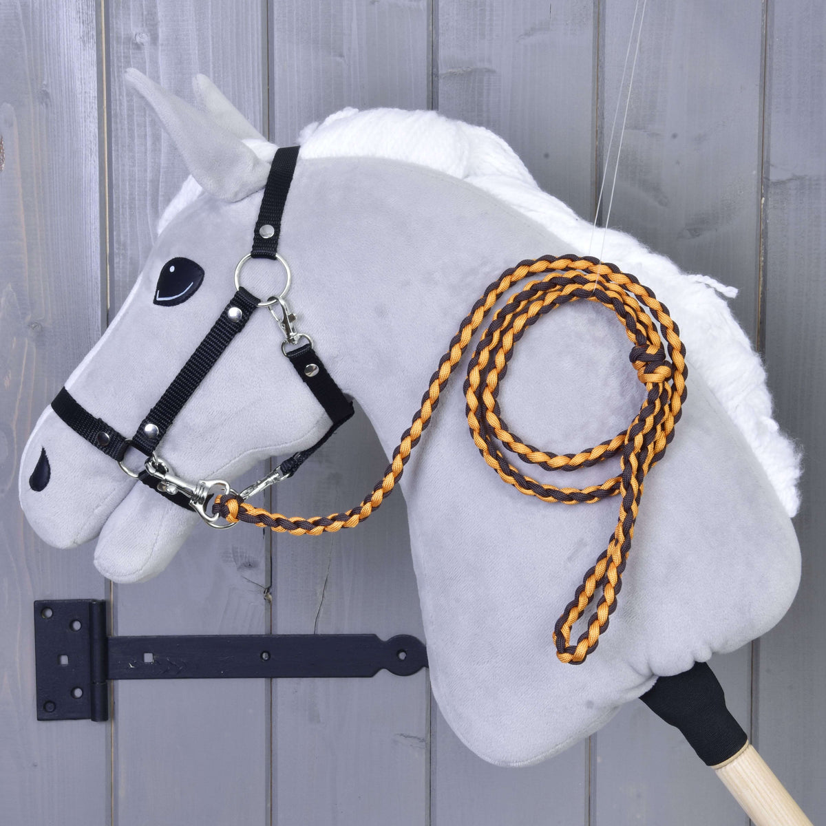 Orange and black braided lead rope clipped to the black halter of a grey Hobby Horse with white mane