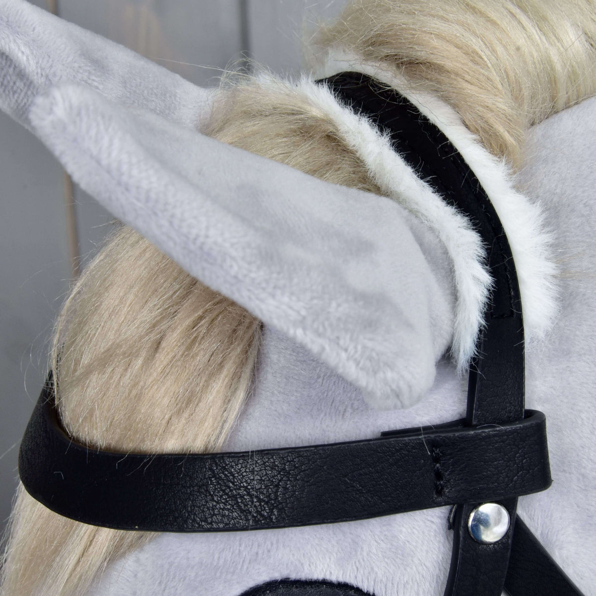 Close-up of the crownpiece lined with white fur behind the ear and the black leatherette browband with a silver rivet
