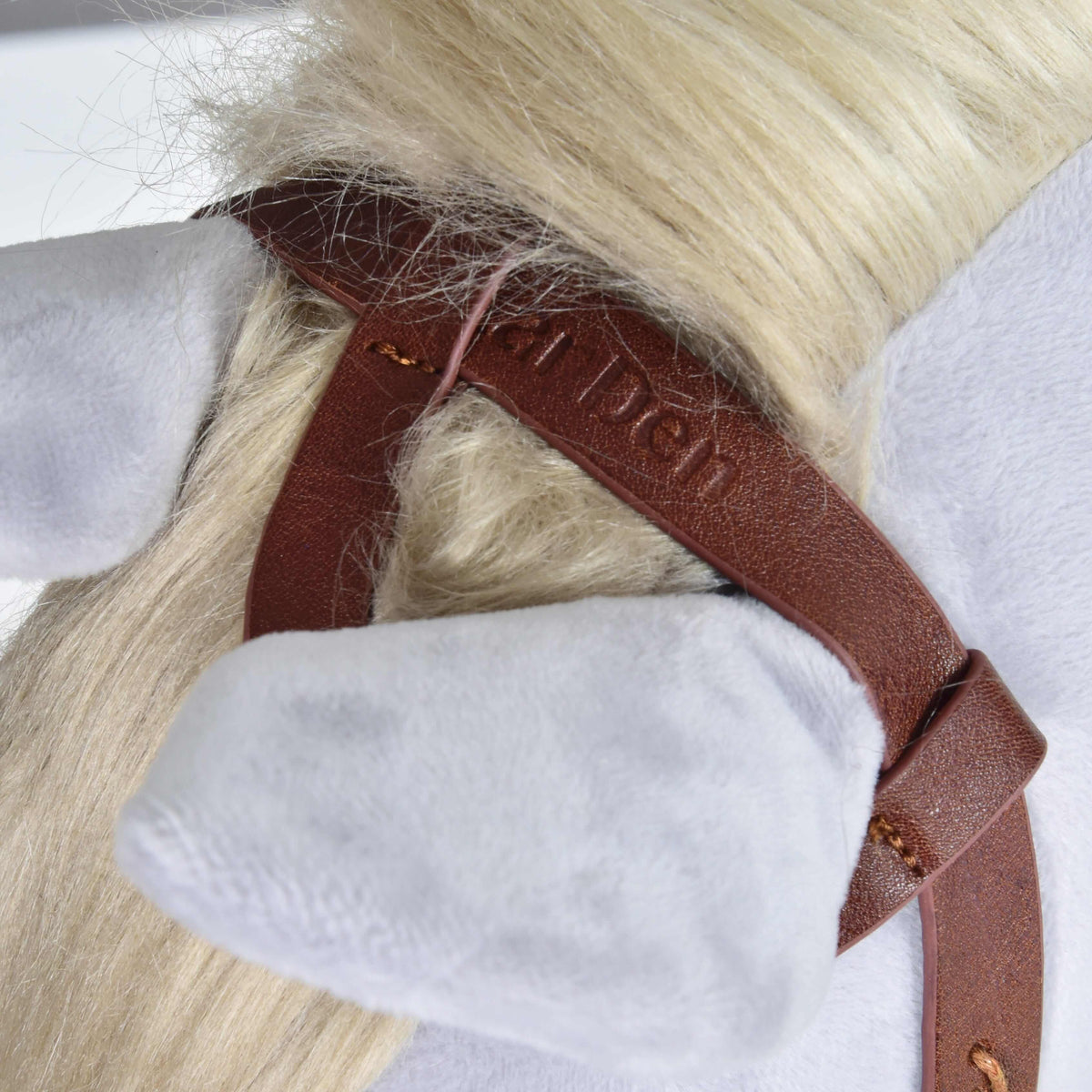 Close-up of the brown crownpiece with embossed lettering, resting in the cream mane behind the ear